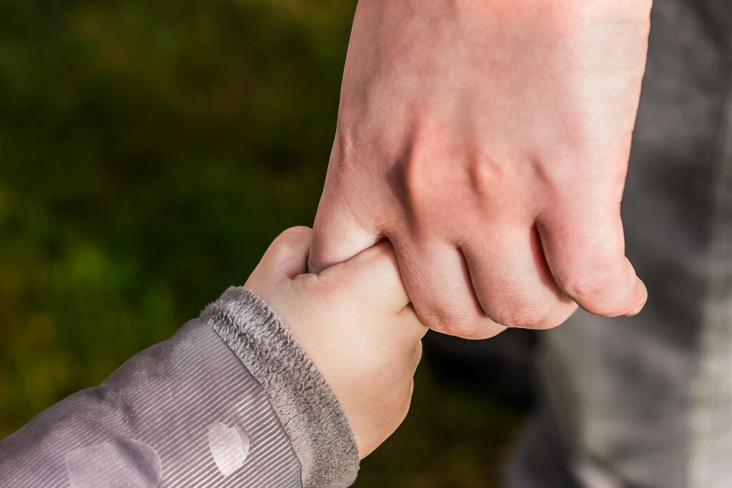 Ein Kind hält die Hand eines Erwachsenen